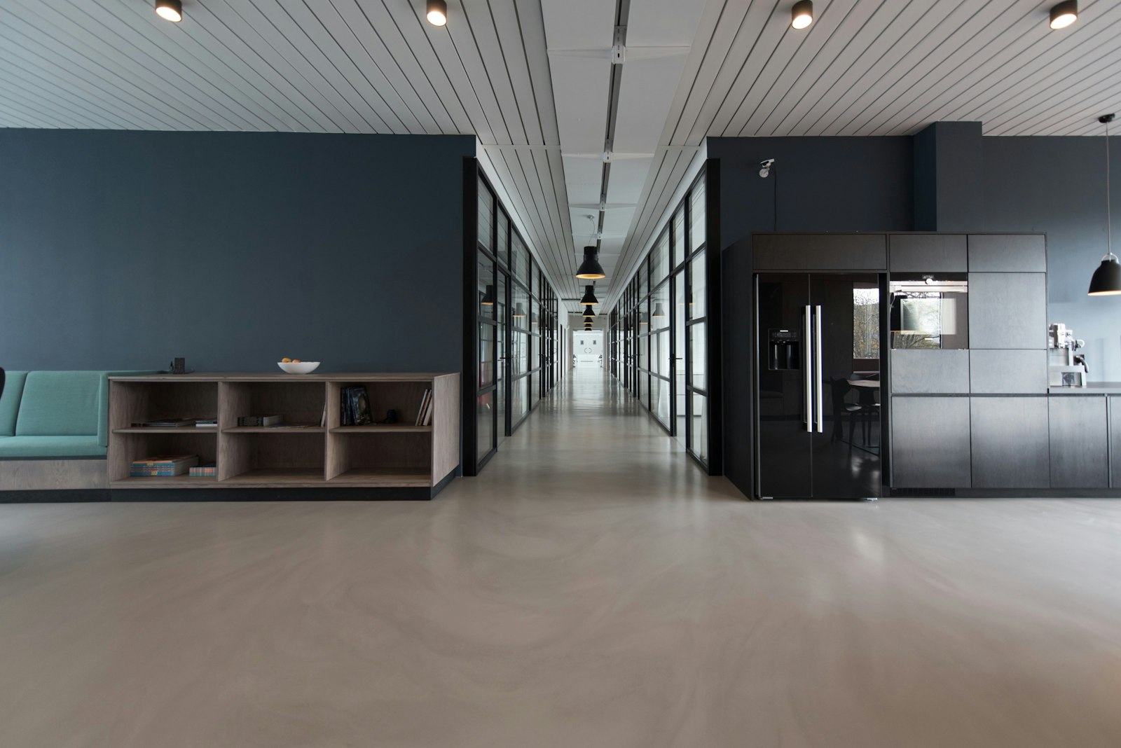 A quiet modern office corridor with glass meeting rooms
